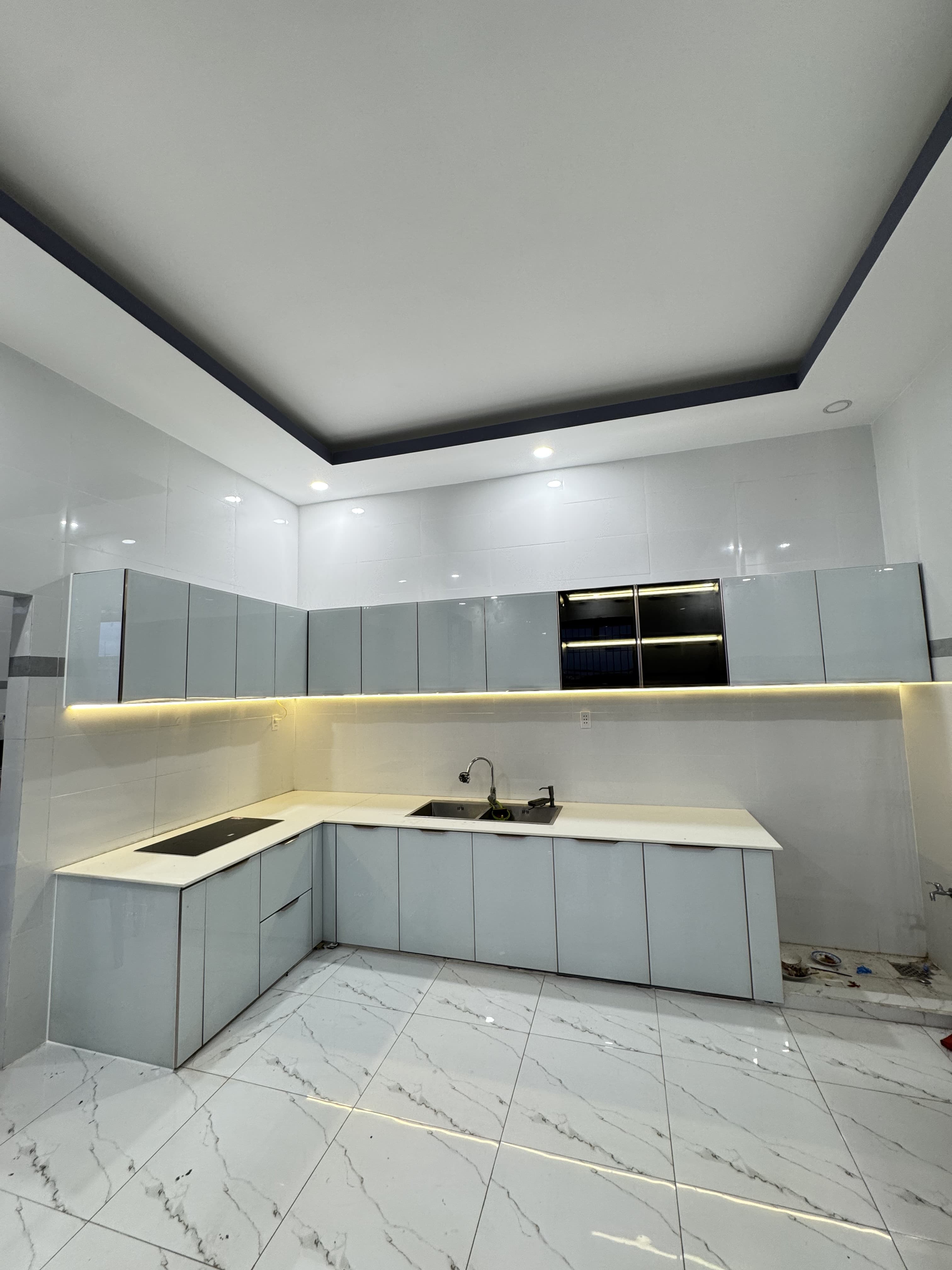 Tủ bếp cánh kính xám có hệ đèn LED chiếu sáng khu vực thao tác