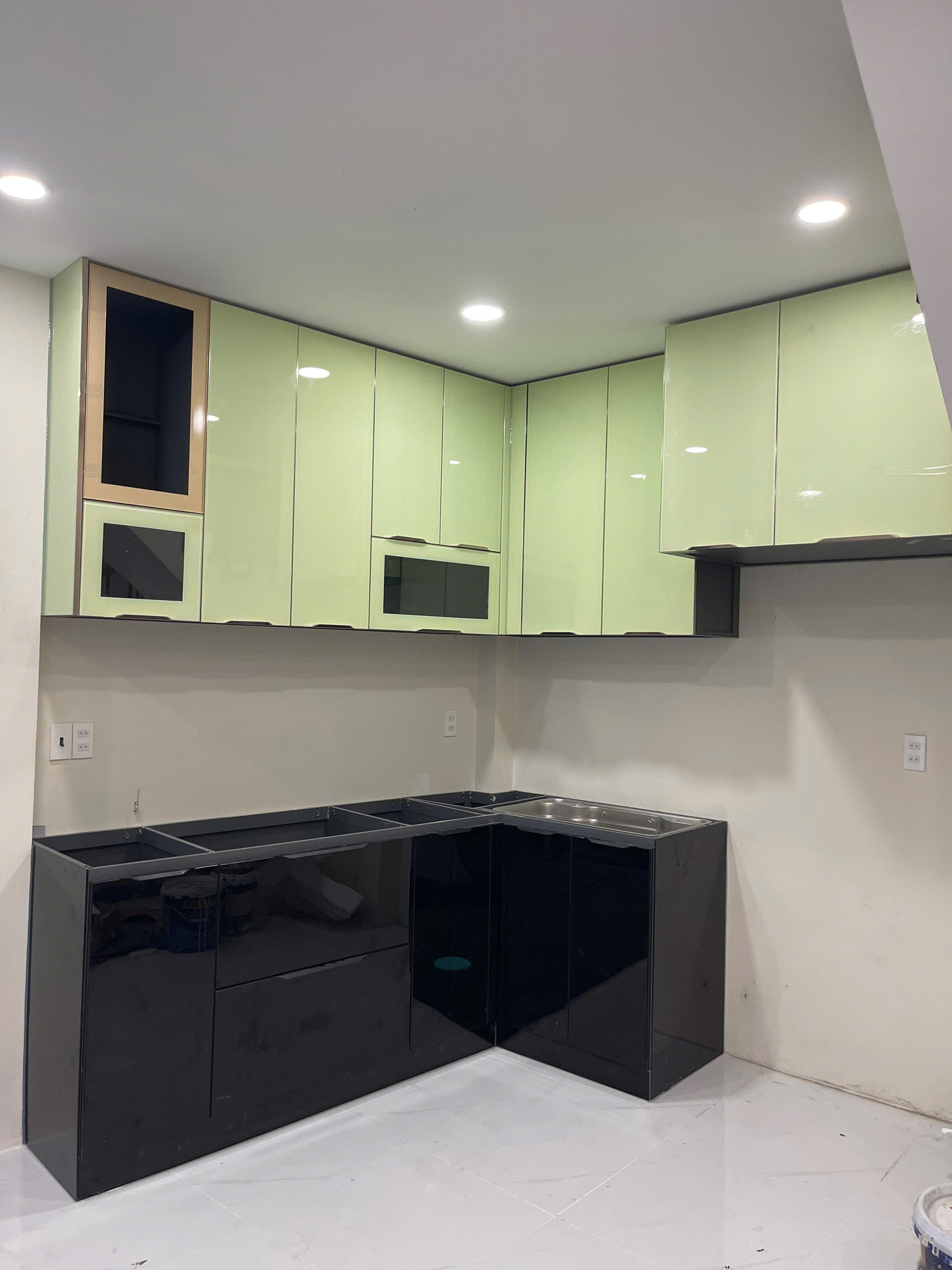 Tủ bếp chữ L màu xanh nhạt được chụp trực tiếp tại công trình thực tế