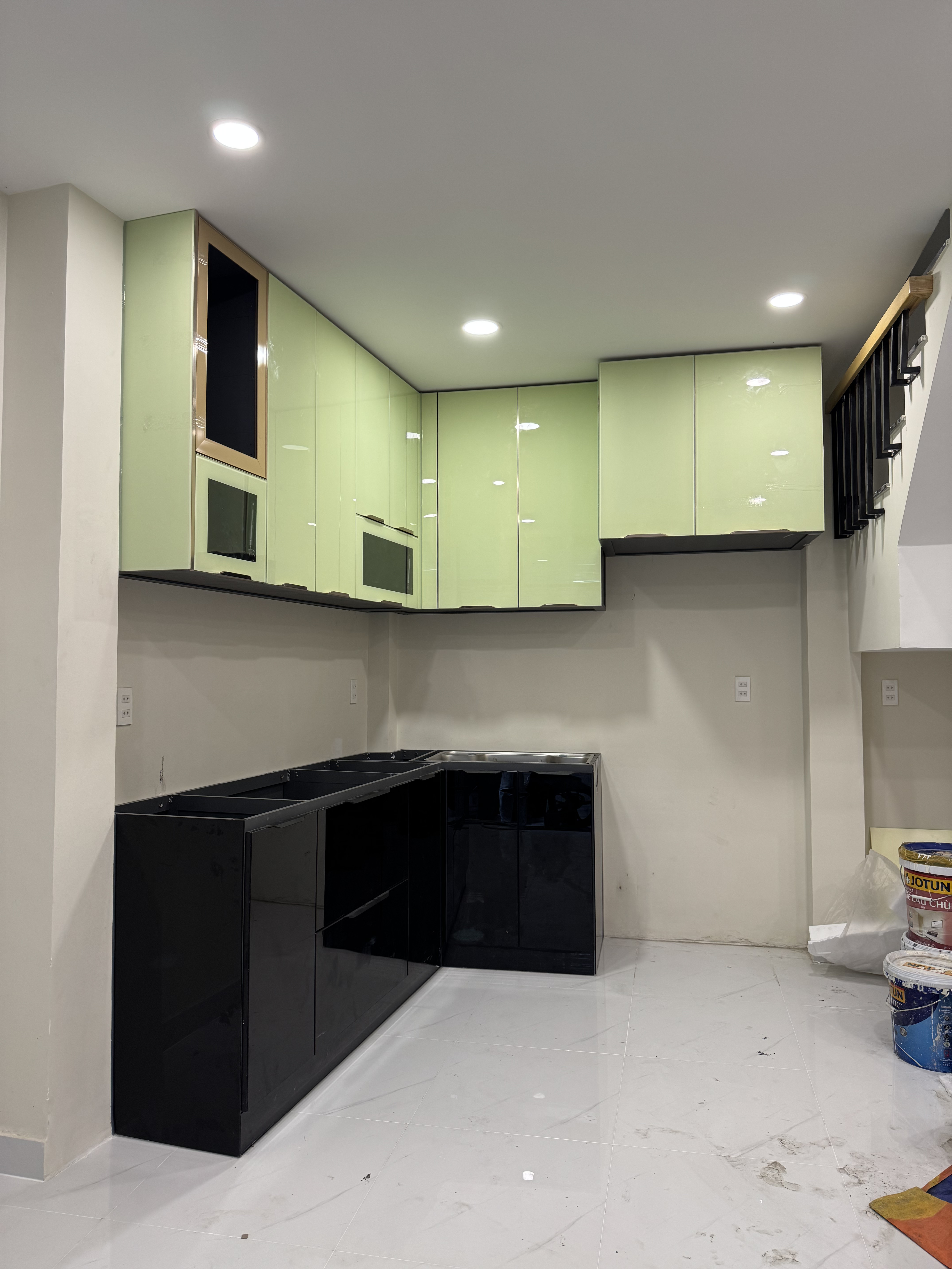 Tủ bếp chữ L màu xanh nhạt được chụp trực tiếp tại công trình thực tế