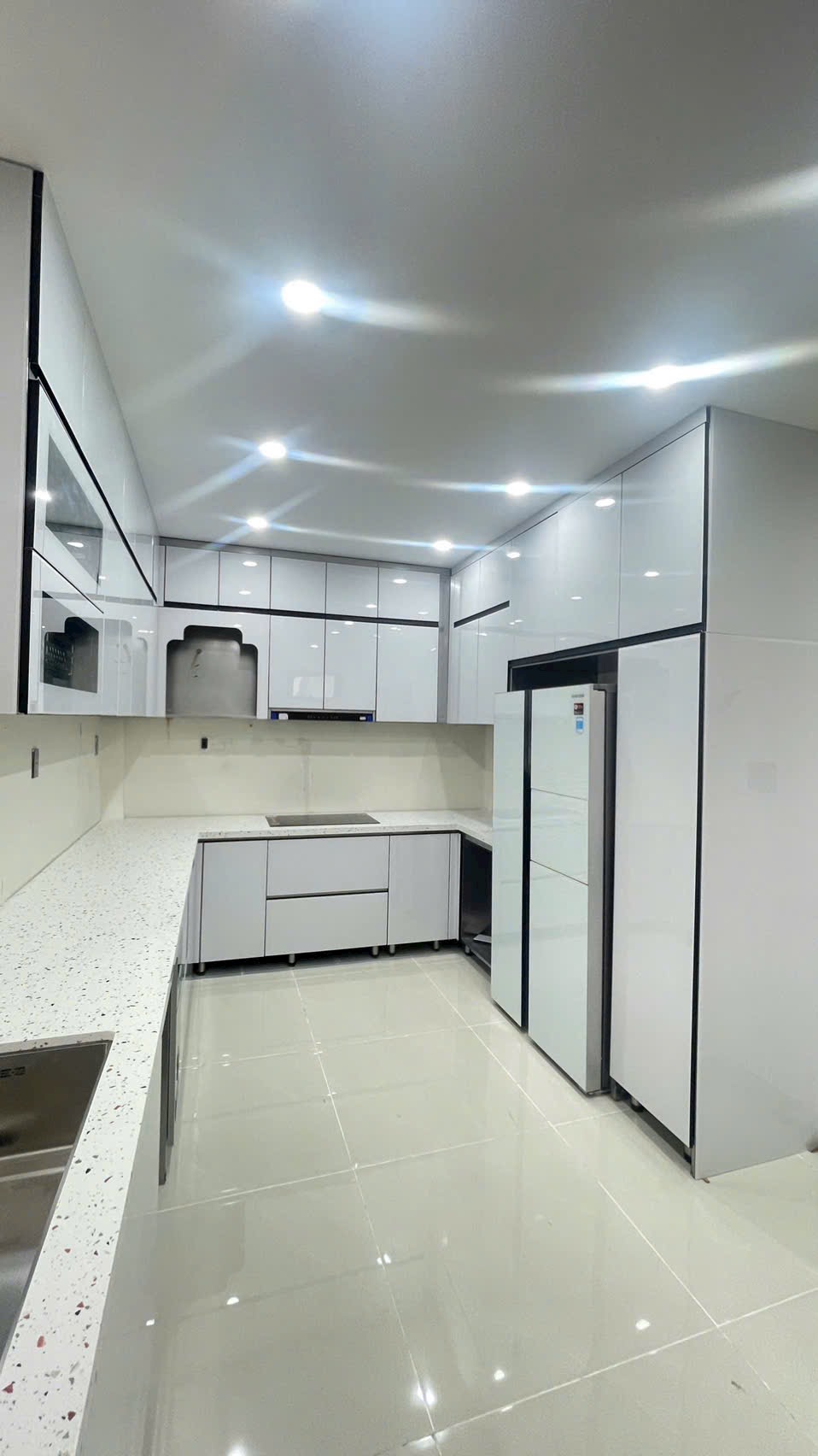 Tủ bếp cánh kính trắng hoàn thiện được chụp trực tiếp tại công trình thực tế