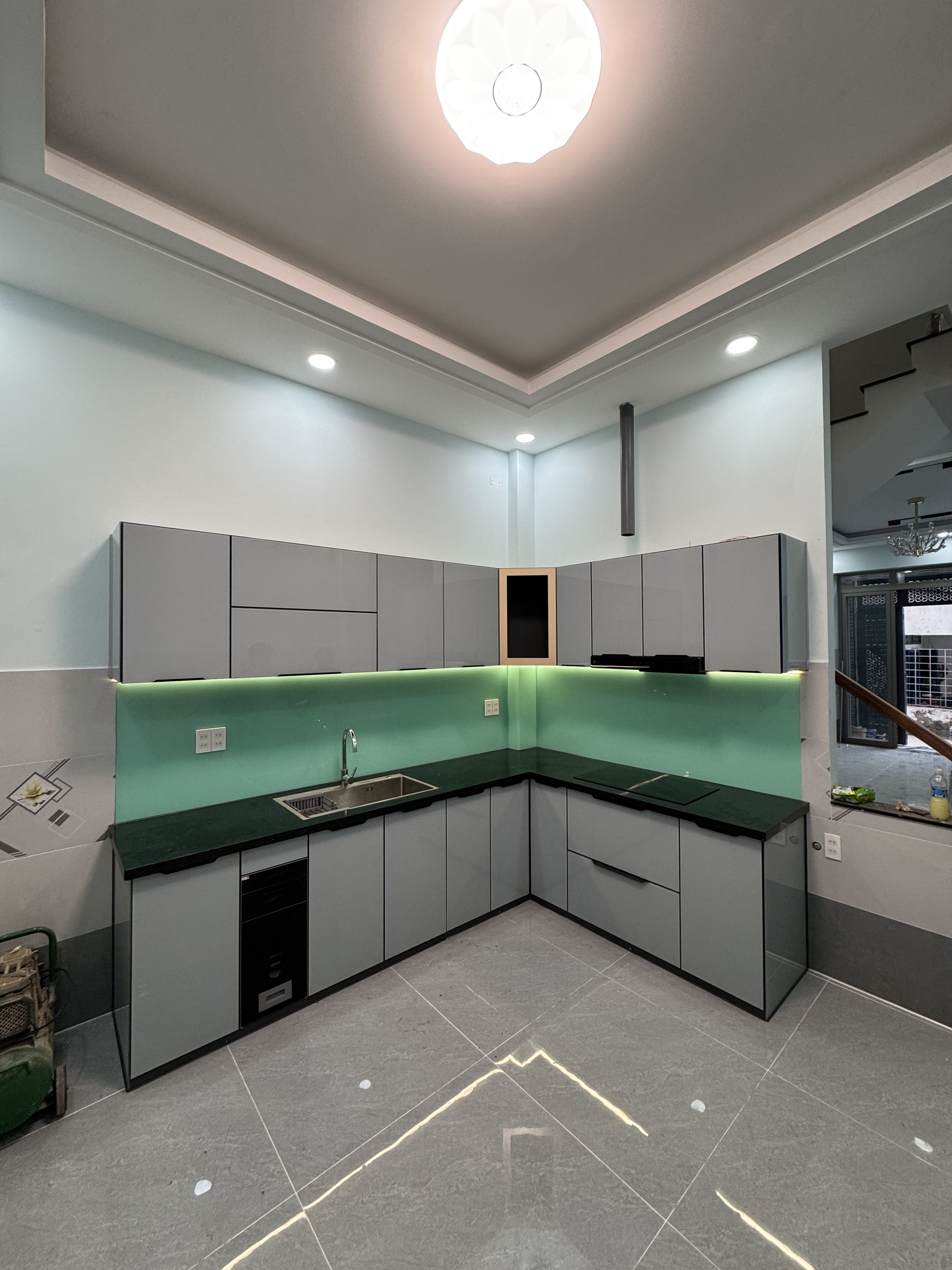 Tủ bếp chữ L cánh kính xám được chụp trực tiếp tại công trình thực tế