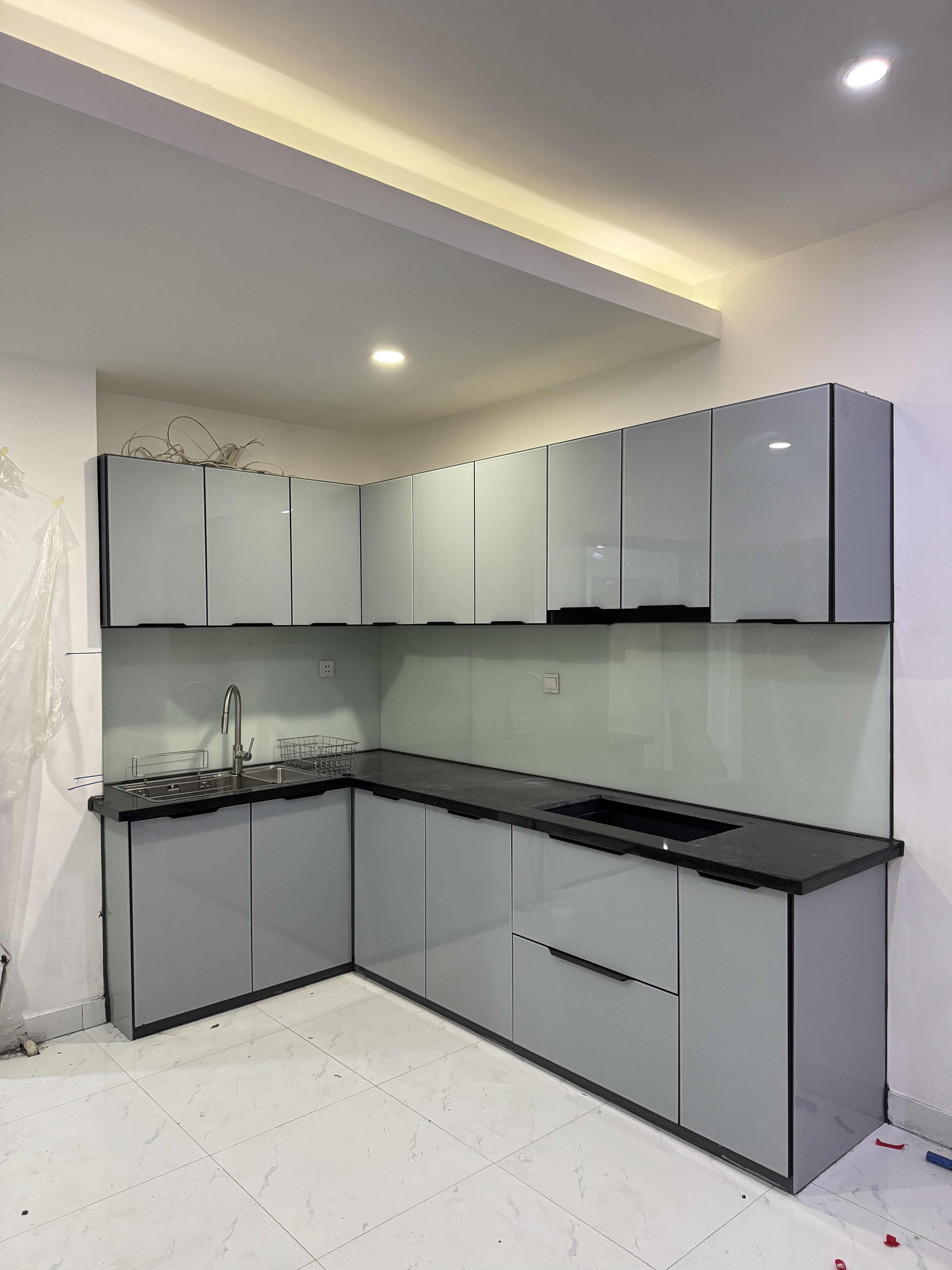 Tủ bếp cánh kính xám hoàn thiện được chụp trực tiếp tại công trình thực tế