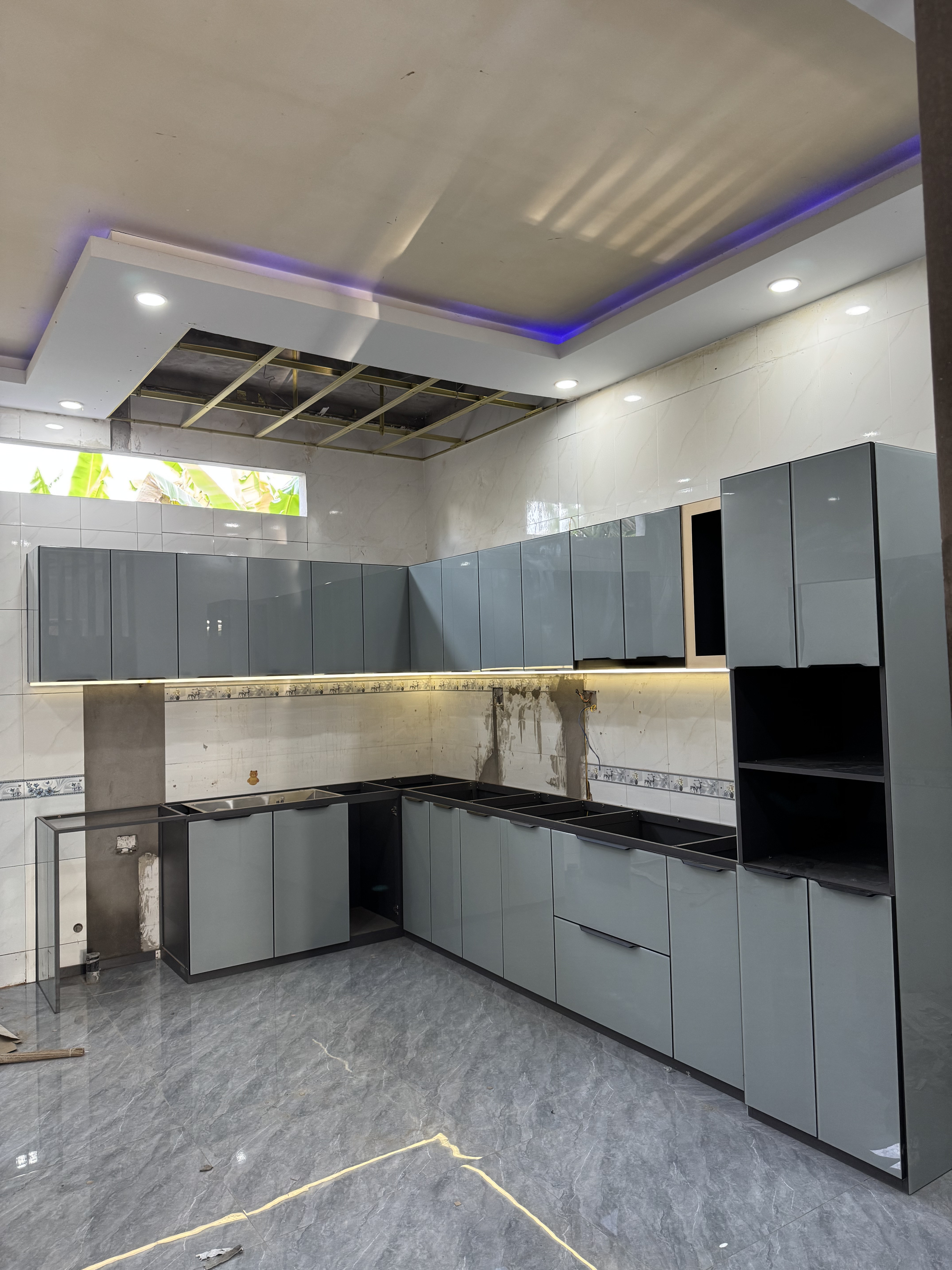 Tủ bếp cánh kính xám tại công trình được chụp trực tiếp tại công trình thực tế